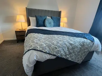 a bedroom with a large bed with blue pillows at Comfy and Connected Standish Home - Two Mins from M6 Jct-27 in Standish
