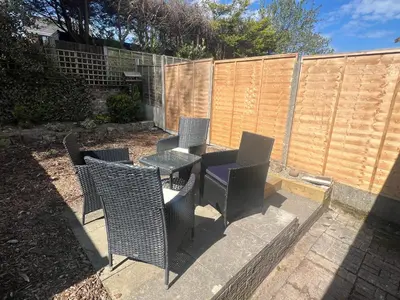 a patio with chairs and a table and a fence at Comfy and Connected Standish Home - Two Mins from M6 Jct-27 in Standish