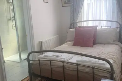a small bedroom with a bed with a pink pillow at Sleeps 7 Home Blackpool w Free Parking BBq WiFi in Blackpool
