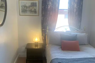 a bedroom with a bed with a lamp and a window at Sleeps 7 Home Blackpool w Free Parking BBq WiFi in Blackpool