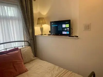 a bedroom with a bed and a television on a shelf at Sleeps 7 Home Blackpool w Free Parking BBq WiFi in Blackpool