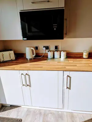 a kitchen counter with white cabinets and a microwave at Wilerby Winchester in Heysham