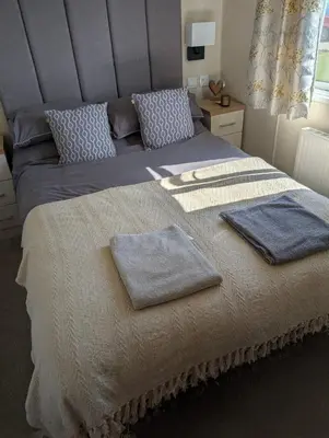 a bedroom with a large bed with two towels on it at Wilerby Winchester in Heysham