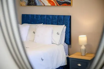 a bed with a blue headboard in a bedroom at Luxury Modern Home Great Harwood - Sleeps Up to 8 in Great Harwood