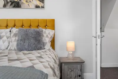 a bedroom with a bed and a table with a lamp at Luxury Modern Home Great Harwood - Sleeps Up to 8 in Great Harwood