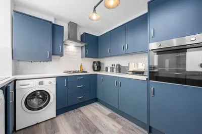 a kitchen with blue cabinets and a washing machine at Luxury Modern Home Great Harwood - Sleeps Up to 8 in Great Harwood