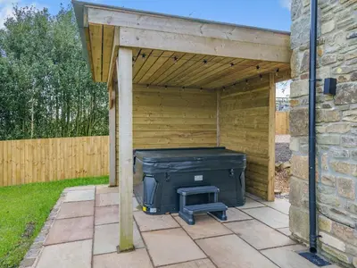 a patio with a large black object under a wooden structure at Meadow View - Uk49066 in Mellor