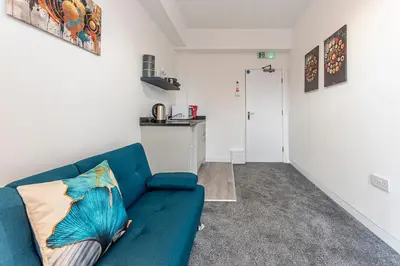 a living room with a blue couch and a kitchen at The Sage in Lytham St Annes