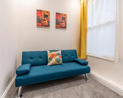 a blue couch in a room with a window at The Sage in Lytham St Annes