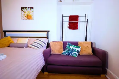 a bedroom with a bed and a couch with pillows at Edinburgh Road Guest House in Liverpool