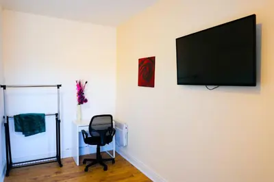 a room with a chair and a flat screen tv on a wall at Edinburgh Road Guest House in Liverpool