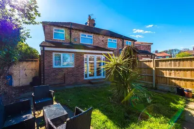 a brick house with blue windows and a fence at Charming Home in Merseyside, sleeps 7 in Liverpool