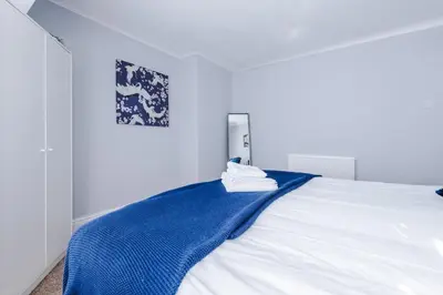 a white bed with a blue blanket on it at Charming Home in Merseyside, sleeps 7 in Liverpool