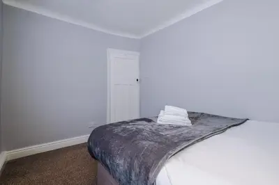a white bedroom with a bed with a blanket on it at Charming Home in Merseyside, sleeps 7 in Liverpool
