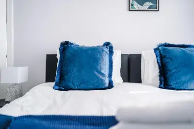 a bed with blue pillows on top of it at Charming Home in Merseyside, sleeps 7 in Liverpool
