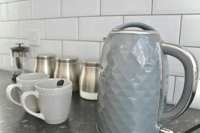 a silver jug sitting on a counter next to cups at Your lovely 3-bed home-from-home in Bamber Bridge in Bamber Bridge
