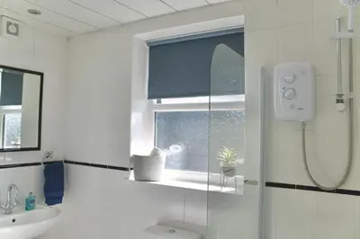 a white bathroom with a shower and a sink at Your lovely 3-bed home-from-home in Bamber Bridge in Bamber Bridge