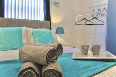 a bed with towels and two cups on a tray at Your lovely 3-bed home-from-home in Bamber Bridge in Bamber Bridge