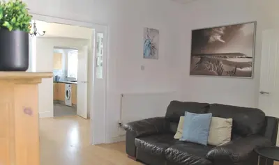 a living room with a leather couch and a kitchen at Your lovely 3-bed home-from-home in Bamber Bridge in Bamber Bridge