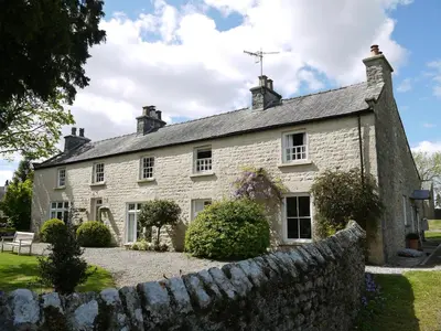 an old stone house with a stone wall at 1 The Green in Carnforth