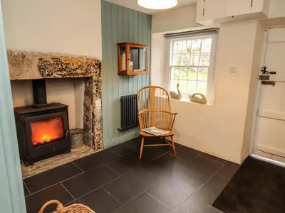 a living room with a fireplace and a chair at 1 The Green in Carnforth