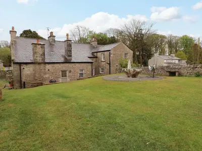 an old stone house with a large grass yard at 1 The Green in Carnforth