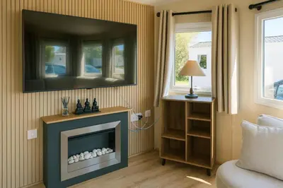 a living room with a fireplace with a tv above it at 12a Mill View 4 Bed Static Caravan Marton Mere in Blackpool