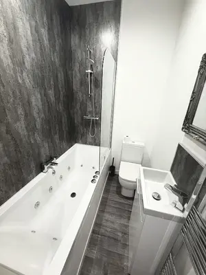 a black and white bathroom with a tub and a toilet at Hornby Hottub and Jacuzzi Suites in Blackpool
