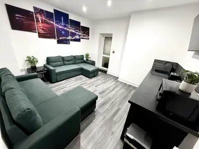 a living room with a green couch and a tv at Hornby Hottub and Jacuzzi Suites in Blackpool