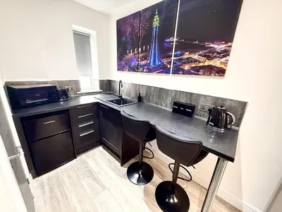 a kitchen with a counter with two chairs and a sink at Hornby Hottub and Jacuzzi Suites in Blackpool