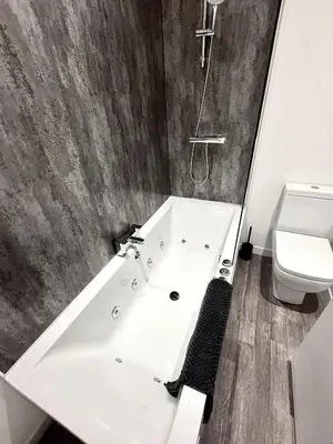 a bathroom with a bath tub and a toilet at Hornby Hottub and Jacuzzi Suites in Blackpool