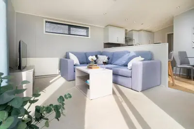 a living room with a blue couch and a table at Silverdale Lodge, HotTub, Wi-FI, Quiet & Sleeps 4 in Warton