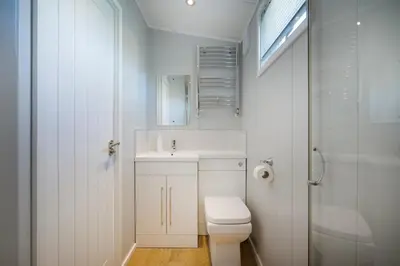 a white bathroom with a toilet and a sink at Silverdale Lodge, HotTub, Wi-FI, Quiet & Sleeps 4 in Warton