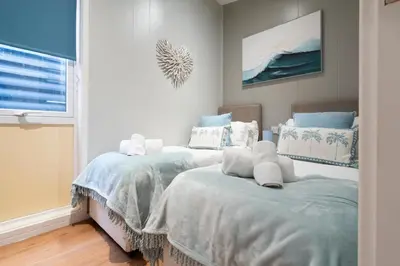 two twin beds in a room with a window at Silverdale Lodge, HotTub, Wi-FI, Quiet & Sleeps 4 in Warton
