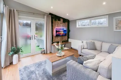 a living room with a couch and a table at Silverdale Lodge, HotTub, Wi-FI, Quiet & Sleeps 4 in Warton