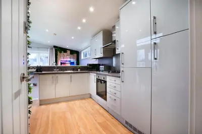 a kitchen with white cabinets and a wooden floor at Silverdale Lodge, HotTub, Wi-FI, Quiet & Sleeps 4 in Warton