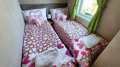 two beds in a room with a window at 95C Sunset View Port Haverigg Marina Village in Millom