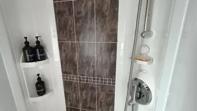 a bathroom with a shower with bottles of wine at 95C Sunset View Port Haverigg Marina Village in Millom