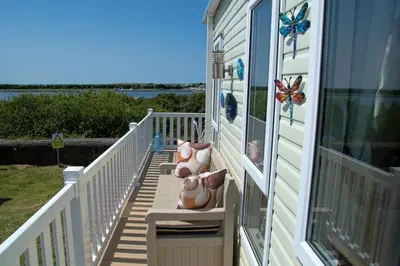 a porch with pink pillows on the side of a house at 95C Sunset View Port Haverigg Marina Village in Millom