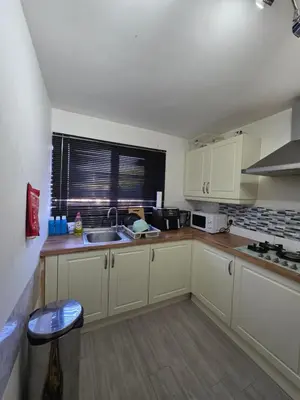 a kitchen with white cabinets and a sink and a window at Serene room in Liverpool