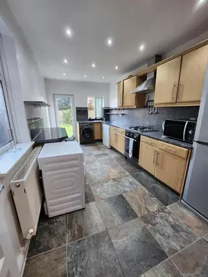 a large kitchen with wooden cabinets and a tile floor at Newly Refurbished 3 Bedroom House with Lovely Garden in Bolton