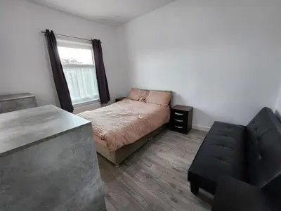 a bedroom with a bed and a couch and a window at Newly Refurbished 3 Bedroom House with Lovely Garden in Bolton