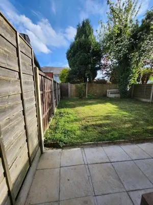 a fence next to a yard with a sidewalk at Newly Refurbished 3 Bedroom House with Lovely Garden in Bolton