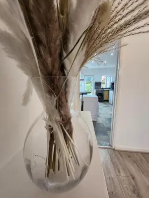 a glass vase with feathers in it on a table at Newly Refurbished 3 Bedroom House with Lovely Garden in Bolton