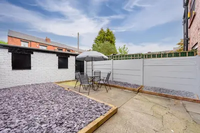 a patio with a table and an umbrella at Free Parking Stunning 3Bedroom Home In Wigan in Wigan