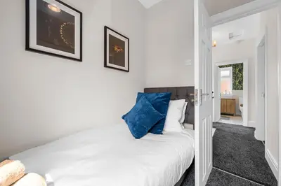 a bedroom with a white bed with blue pillows at Free Parking Stunning 3Bedroom Home In Wigan in Wigan