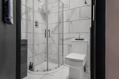 a white bathroom with a shower and a toilet at The Rockfield by Serene Stays Stylish 6BR near Anfield with Bar Virgin Media and Fast WiFi in Liverpool