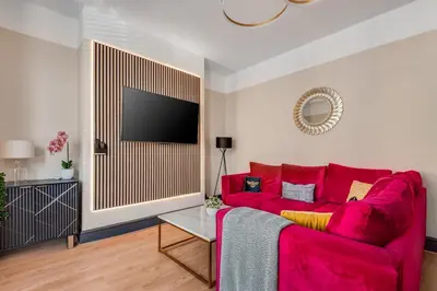 a living room with a red couch and a flat screen tv at The Rockfield by Serene Stays Stylish 6BR near Anfield with Bar Virgin Media and Fast WiFi in Liverpool