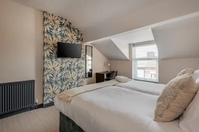 a bedroom with two beds and a tv on a wall at The Rockfield by Serene Stays Stylish 6BR near Anfield with Bar Virgin Media and Fast WiFi in Liverpool
