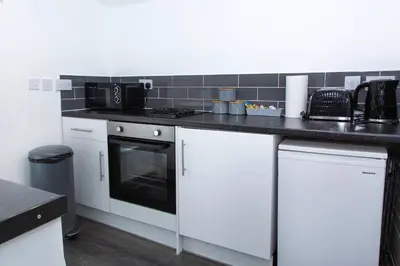 a kitchen with white cabinets and a black counter top at Snuggle Cove Apartments- Walton Road in Liverpool